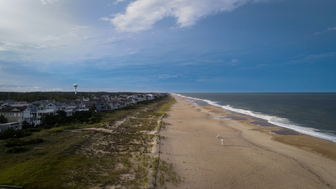 Photo of a Delaware coastal home under construction showing elevated foundation, pilings, and framing near dunes