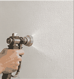 Texture being sprayed onto smooth drywall surface