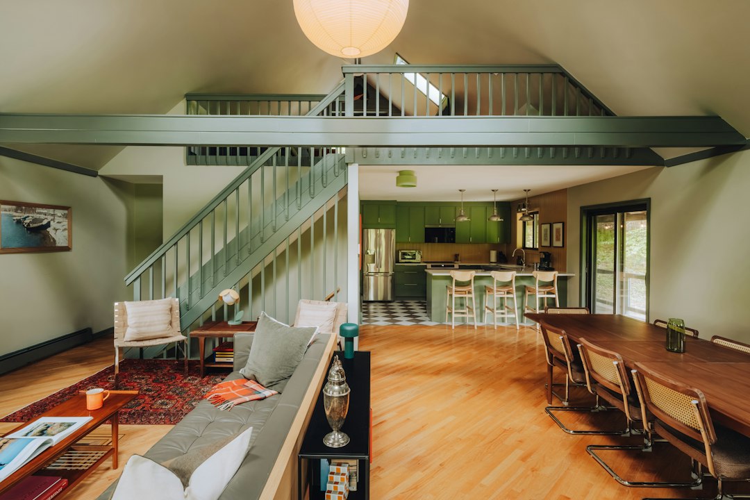 Open-plan barndominium interior with a loft, exposed structure and a kitchen at the far end