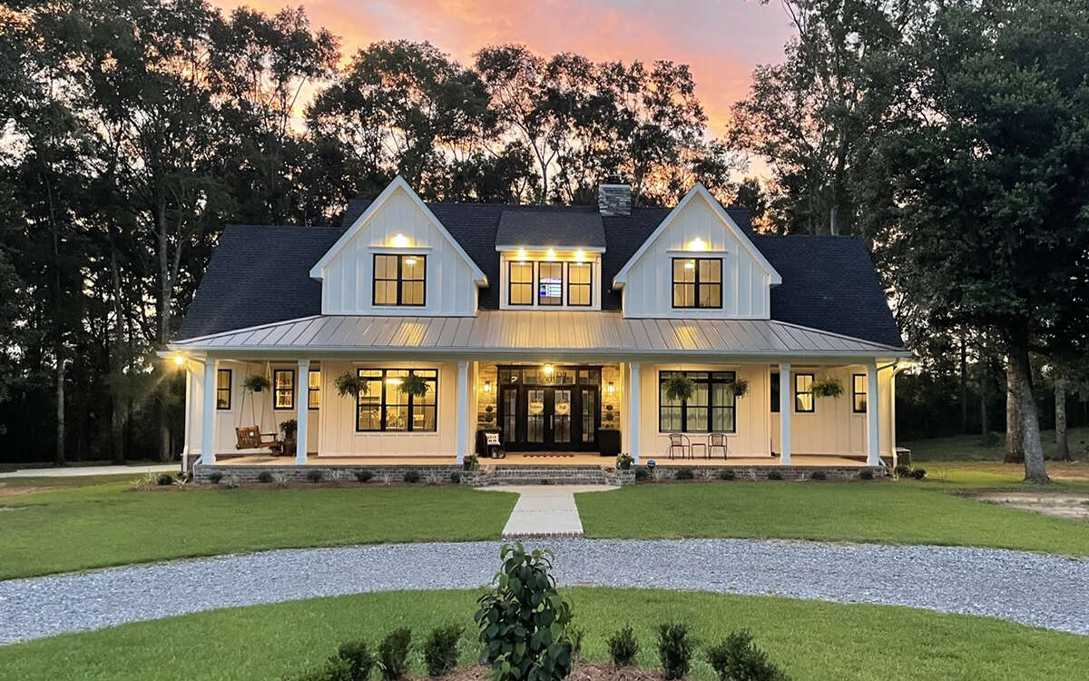 Front exterior rendering of Modern Farmhouse Plan 098-00316, a two-story symmetrical design with a full-width covered front porch, gabled roofline, stacked stone accents, and a side-entry three-car garage